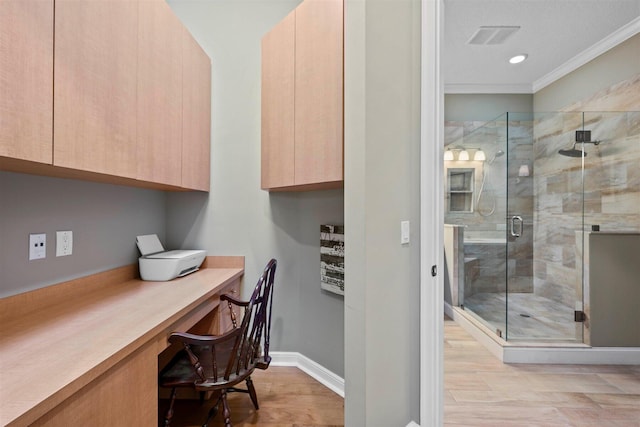 home office with light hardwood / wood-style flooring, built in desk, and ornamental molding