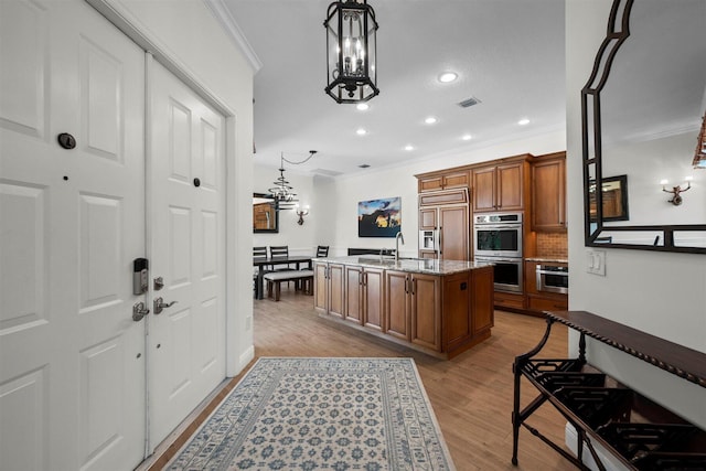 kitchen featuring paneled built in fridge, a chandelier, light hardwood / wood-style floors, and stone countertops