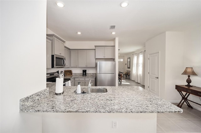 kitchen featuring light stone counters, stainless steel appliances, light tile floors, sink, and gray cabinets