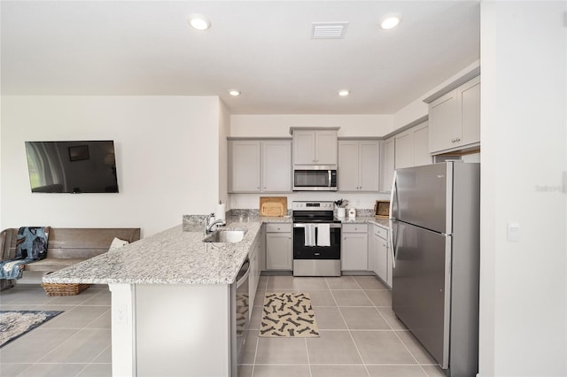 kitchen featuring appliances with stainless steel finishes, light stone countertops, kitchen peninsula, and light tile floors