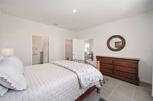 bedroom with a closet, a spacious closet, ensuite bathroom, and light tile flooring