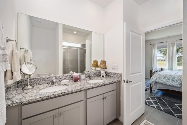 bathroom featuring tile floors, toilet, a shower with door, and double vanity