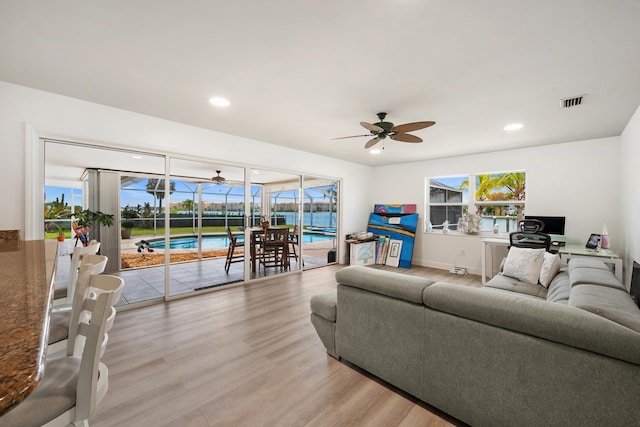 living room with plenty of natural light, ceiling fan, and light wood-type flooring