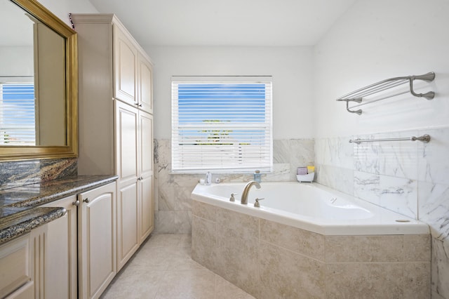 bathroom featuring tiled tub, vanity, and tile patterned flooring