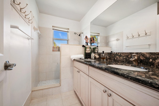 bathroom with a tile shower, tile patterned flooring, and double vanity