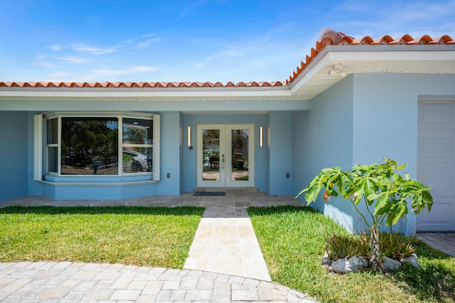 view of exterior entry featuring french doors and a yard