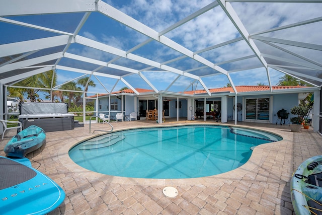 view of pool with a patio, glass enclosure, and a hot tub