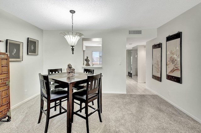 dining area featuring light carpet, a textured ceiling, and a notable chandelier