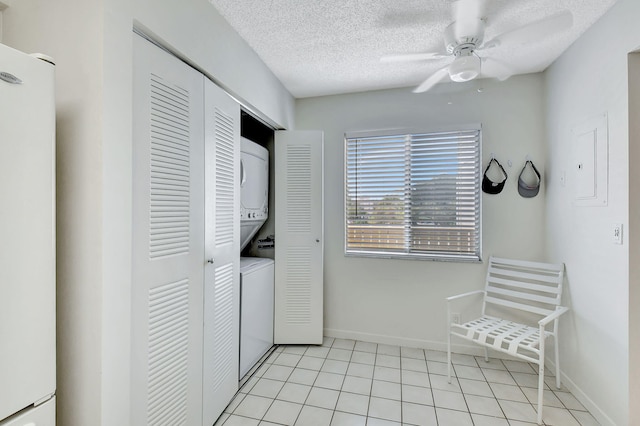 clothes washing area featuring electric panel, ceiling fan, a textured ceiling, light tile patterned flooring, and stacked washer / dryer