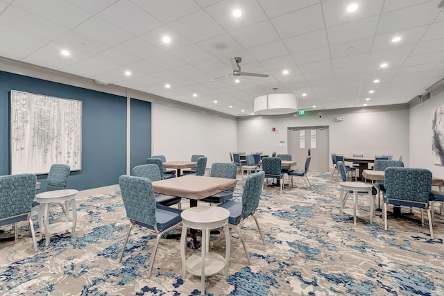 carpeted dining space with ceiling fan and crown molding