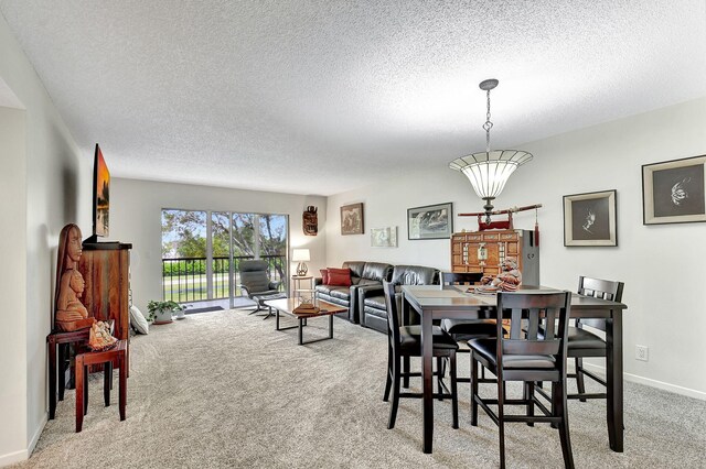 dining room featuring light colored carpet and a textured ceiling