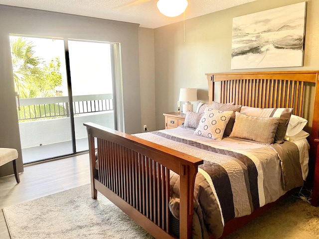 bedroom featuring a textured ceiling, light wood-type flooring, and access to outside