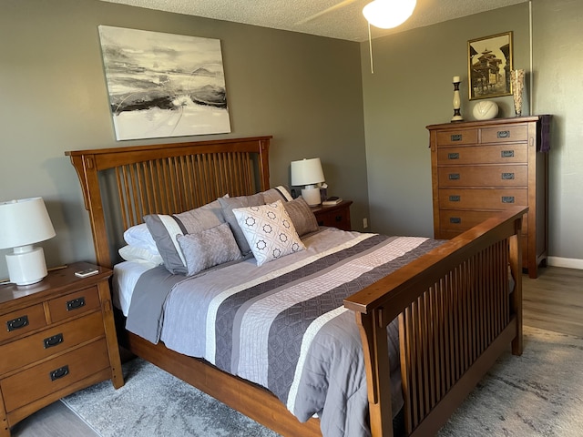 bedroom with a textured ceiling, ceiling fan, and light wood-type flooring