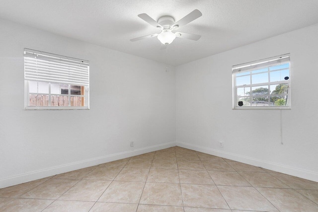 empty room with ceiling fan, a textured ceiling, and light tile patterned floors