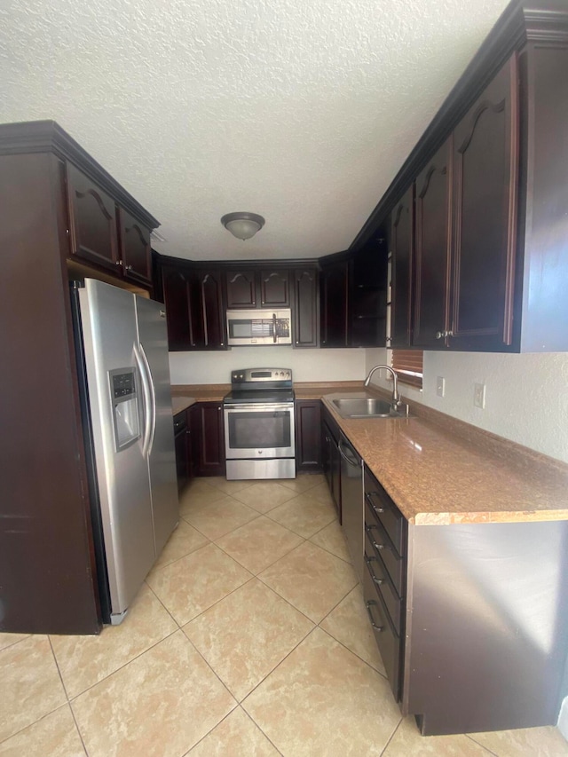 kitchen featuring dark brown cabinets, a textured ceiling, stainless steel appliances, and sink