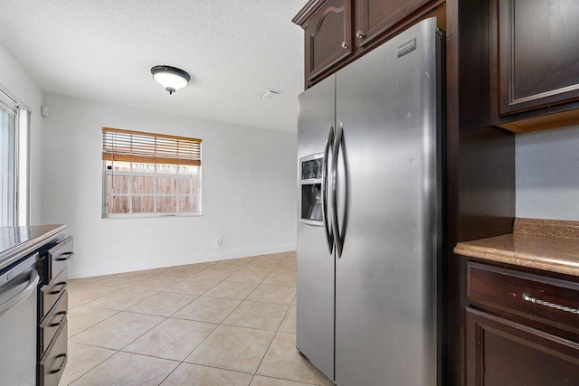 kitchen with dark brown cabinets, light tile patterned flooring, a textured ceiling, and appliances with stainless steel finishes