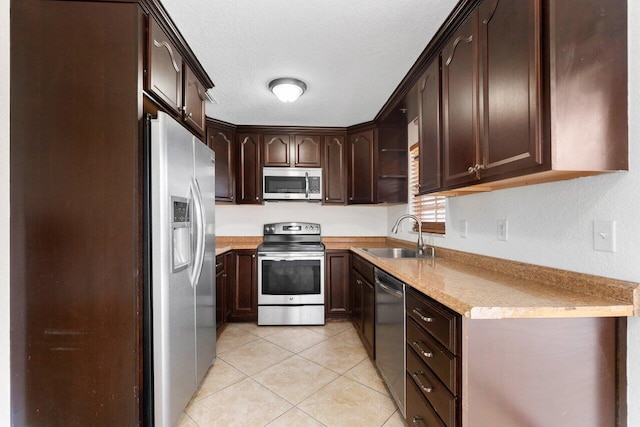 kitchen featuring sink, a textured ceiling, dark brown cabinets, light tile patterned floors, and stainless steel appliances