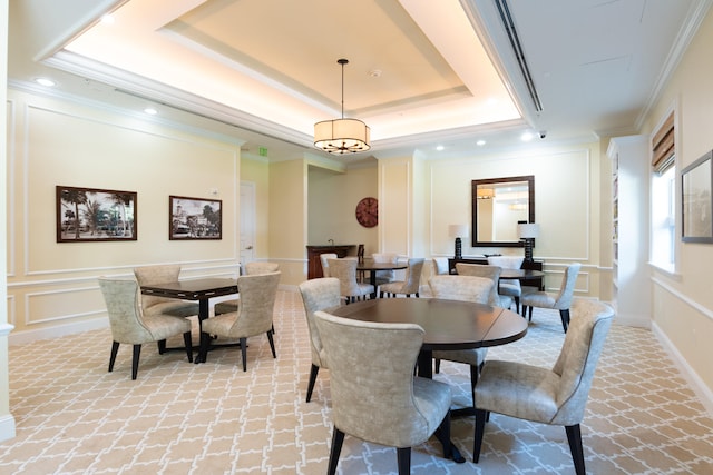 dining room featuring an inviting chandelier, a raised ceiling, and ornamental molding