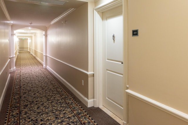 hallway featuring dark colored carpet and ornamental molding