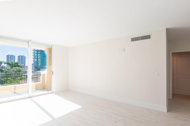 unfurnished room featuring a wall of windows and light wood-type flooring