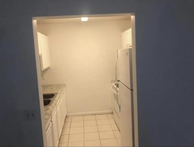 kitchen featuring white cabinets, white fridge, light tile floors, and sink