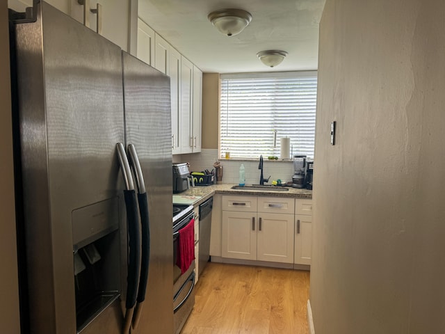 kitchen featuring light hardwood / wood-style floors, tasteful backsplash, sink, white cabinets, and appliances with stainless steel finishes