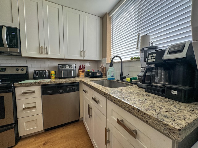 kitchen featuring sink, tasteful backsplash, light wood-type flooring, and appliances with stainless steel finishes