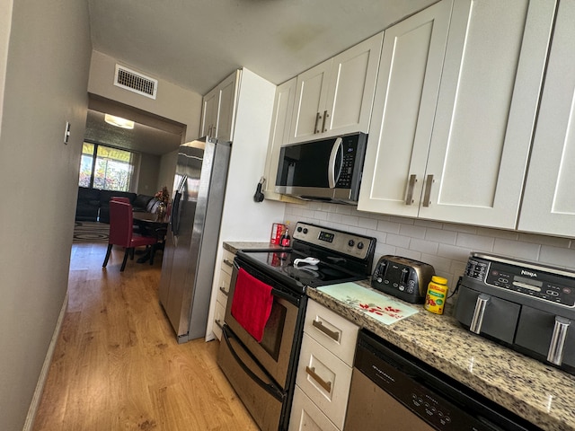 kitchen with light hardwood / wood-style flooring, stainless steel appliances, light stone counters, backsplash, and white cabinets