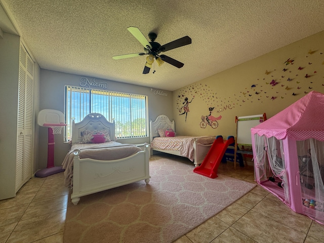 bedroom with tile floors, ceiling fan, a closet, and a textured ceiling