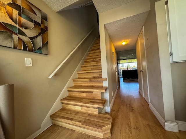 staircase featuring a textured ceiling and wood-type flooring