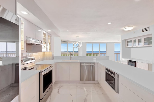 kitchen featuring a sink, electric stove, under cabinet range hood, dishwasher, and modern cabinets