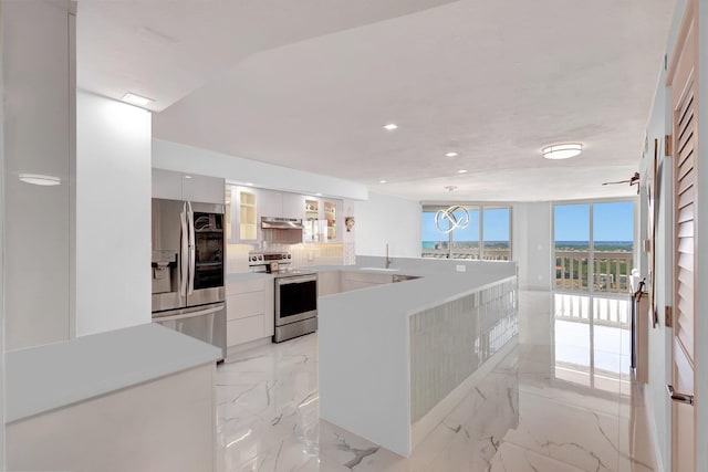 kitchen featuring a peninsula, a sink, appliances with stainless steel finishes, modern cabinets, and marble finish floor