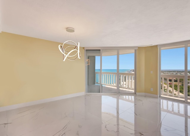 unfurnished room featuring marble finish floor, floor to ceiling windows, a healthy amount of sunlight, and baseboards