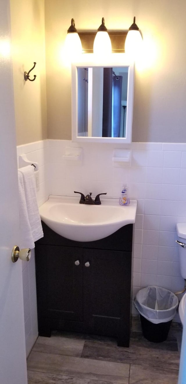 bathroom featuring vanity with extensive cabinet space, toilet, and tile walls