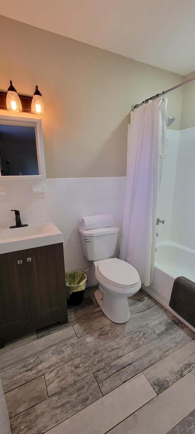 full bathroom featuring toilet, shower / bath combo, vanity, tasteful backsplash, and tile walls