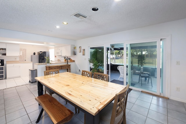 tiled dining space with a textured ceiling