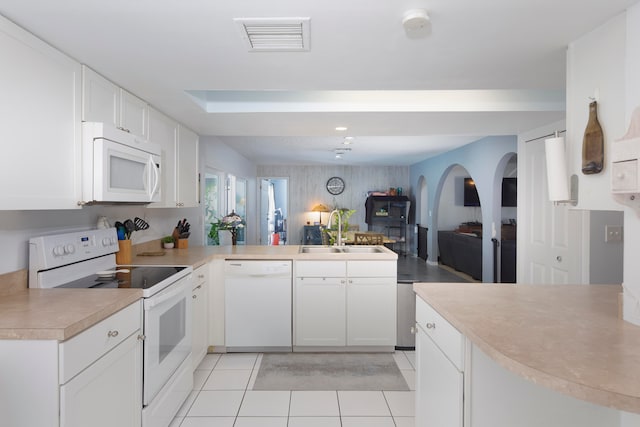 kitchen featuring kitchen peninsula, white appliances, sink, light tile floors, and white cabinetry