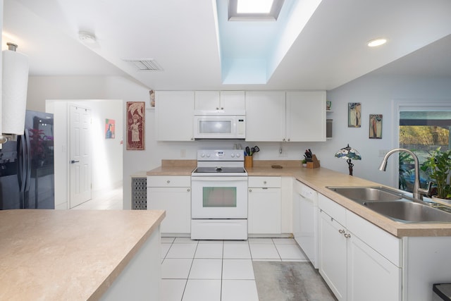 kitchen featuring a skylight, white cabinetry, light tile floors, white appliances, and sink