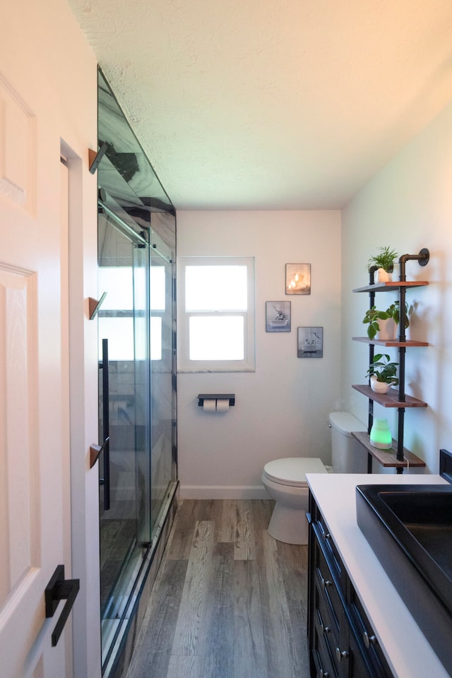 bathroom with toilet, vanity, a shower with shower door, and wood-type flooring