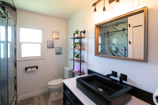 bathroom featuring a shower with shower door, oversized vanity, toilet, and hardwood / wood-style flooring