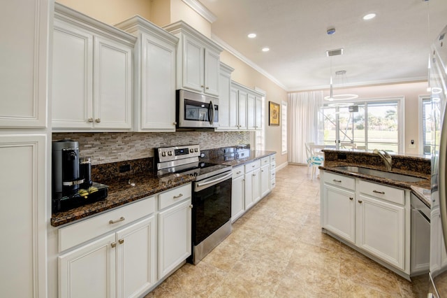 kitchen with appliances with stainless steel finishes, dark stone counters, backsplash, sink, and white cabinets