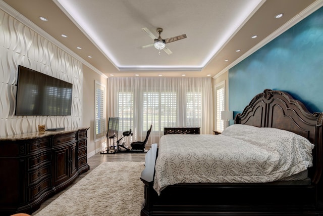 bedroom with a tray ceiling, ornamental molding, ceiling fan, and dark hardwood / wood-style flooring