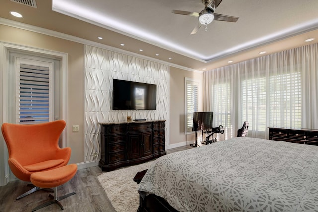 bedroom with ceiling fan, light hardwood / wood-style floors, and a tray ceiling