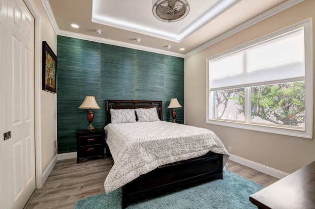 bedroom featuring a tray ceiling and light hardwood / wood-style flooring