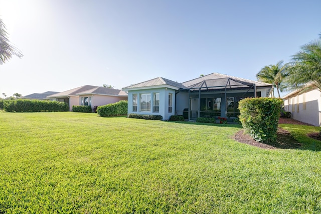 rear view of property featuring a yard and glass enclosure