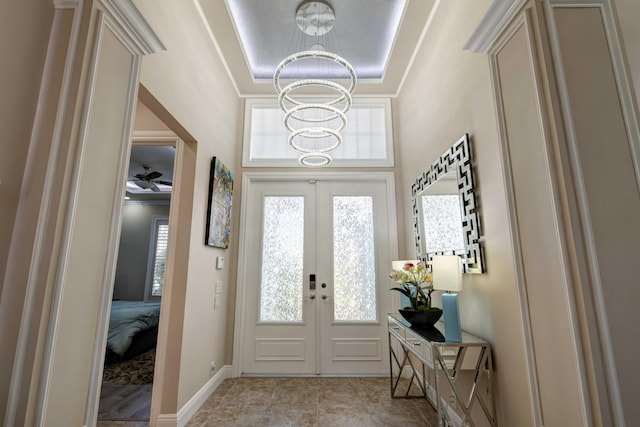 entryway with crown molding, light tile floors, french doors, and ceiling fan with notable chandelier