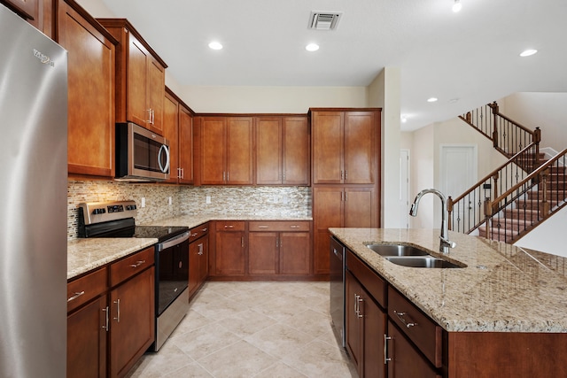 kitchen featuring light stone countertops, backsplash, appliances with stainless steel finishes, sink, and light tile floors