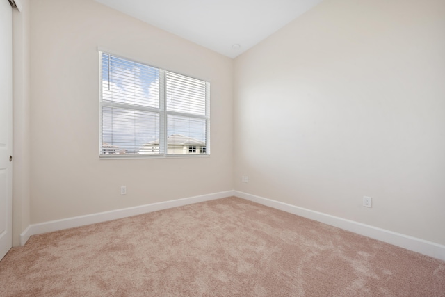 empty room with light carpet and vaulted ceiling