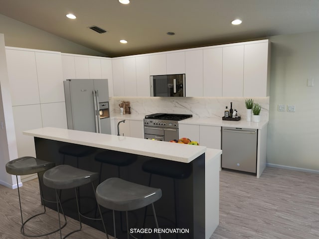 kitchen featuring light hardwood / wood-style flooring, white cabinets, lofted ceiling, and appliances with stainless steel finishes