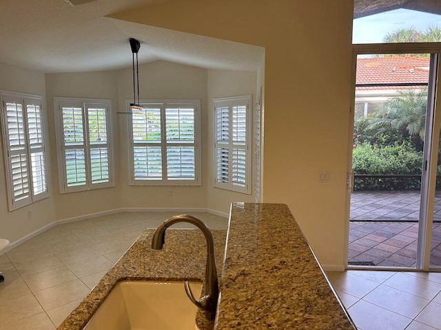 dining space with a textured ceiling, light tile patterned floors, sink, and vaulted ceiling